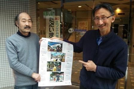 朝日新聞販売所のカレンダーを手にする両氏
